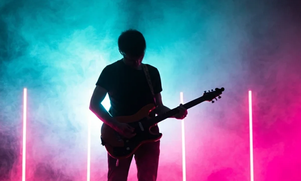 Silhouetted guitarist on a smoke-filled stage under pink and cyan neon lights, evoking 80s synth rock